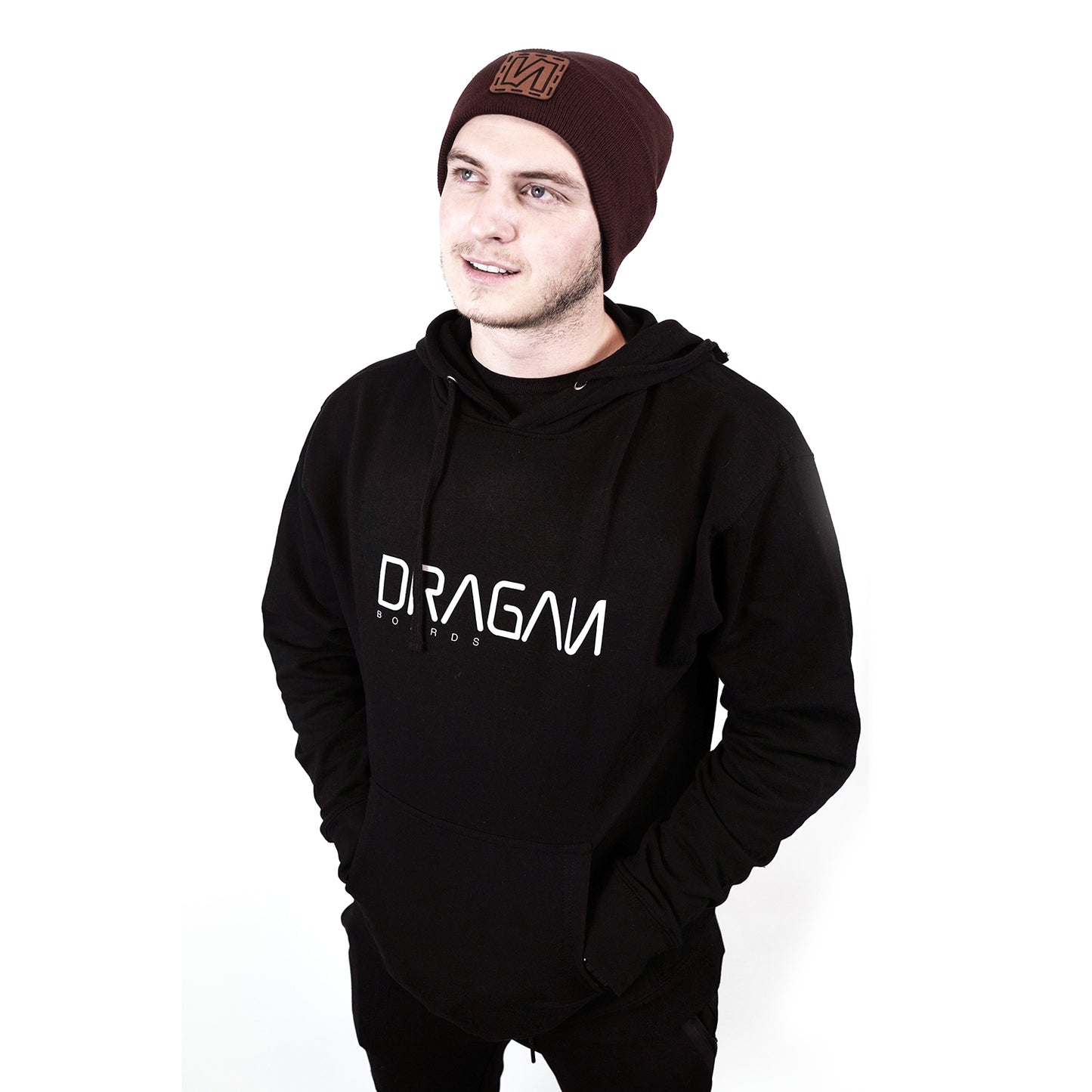 Guy wearing a black hoodie with a Dragan logo on it and a dark red beenie  on a white background